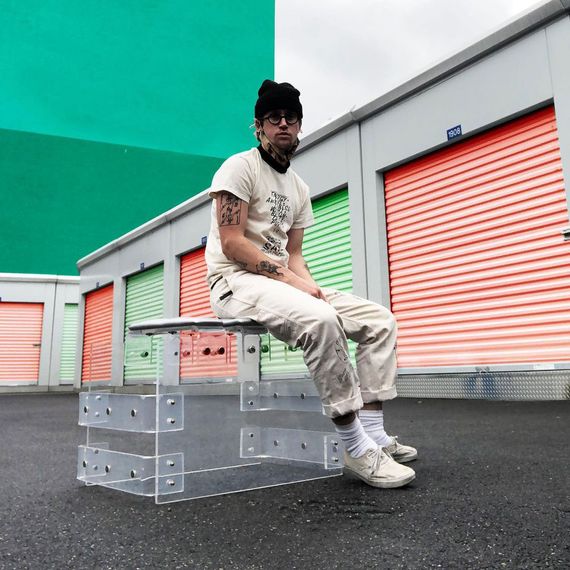 A man sits on a lucite bench in a storage space area.
