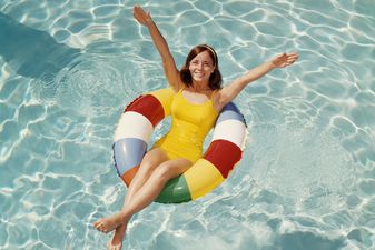 Woman relaxing in pool float tossing beach ball