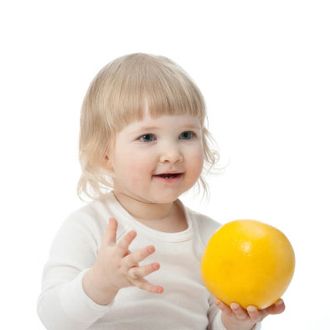 Portrait of baby with a grapefruit on white background