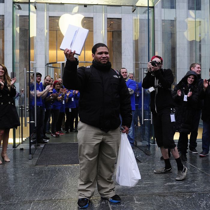 A customer is cheered by Apple employees as he exits from Apple's flagship store on Fifth Avenue after being the first to buy the new iPad at this location, in New York, on March 16, 2012. AFP PHOTO/Emmanuel Dunand.