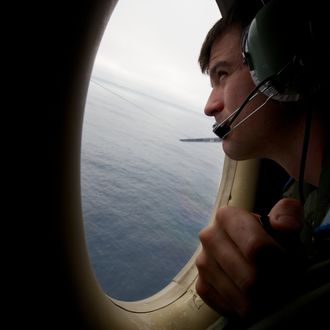 IN FLIGHT - MARCH 24: A crewman of an RAAF AP-3C Orion aircraft looks out from an observation window during a search for missing Malaysia Airways Flight MH370 on March 24, 2014 off the South West Coast of Perth, Australia. Malaysian Prime Minister Najib Razak spoke at a press conference today to announce that fresh analysis of available satellite data has concluded that missing flight MH370's final position was in the southern Indian Ocean. French authorities reported a satellite sighting of objects in an area of the southern Indian Ocean where China and Australia have also reported similar sightings of potential debris from the flight that went missing on March 8. (Photo by Richard Wainwright - Pool/Getty Images)