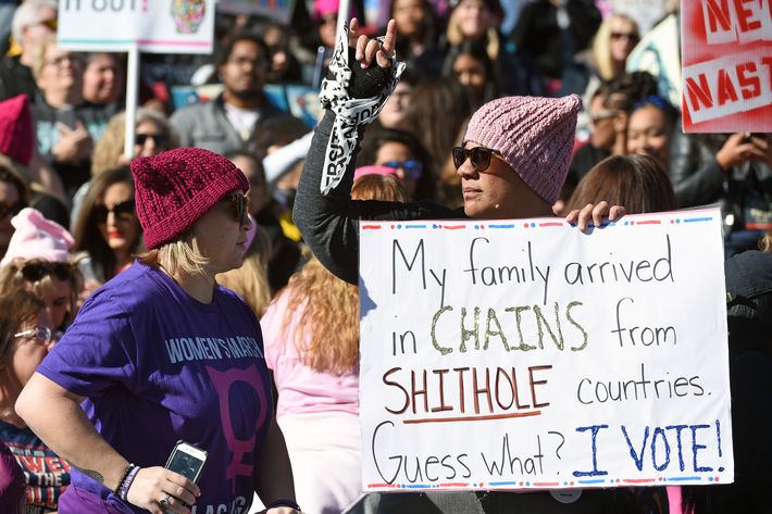 A woman holds up a sign referencing Donald Trump's "shithole countries" remark.