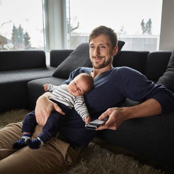 Father and baby boy in living room watching TV