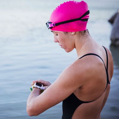 Female open water swimmer checking smart watch at ocean