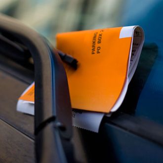 Orange parking ticket placed on windshield of car.