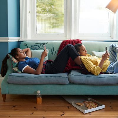 Women using phones while relaxing on sofa