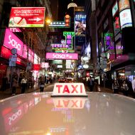 A photo taken on November 19, 2011 shows a taxi driving through the Central district of Hong Kong. As rush hour approaches the streets of Hong Kong, pedestrians can expect to bear witness to a familiar feeding frenzy as scores of shiny red scavengers compete for a sustenance of steady customers. With more than 18,000 taxis plying their trade to a population of over seven million, the night shift is a busy one. For taxi driver Alan Leung, the daily five-hour stint behind the wheel takes him from skyscrapers to street-corners as he traverses the tightly-packed territory in his bright red taxi. AFP PHOTO / ED JONES (Photo credit should read Ed Jones/AFP/Getty Images)