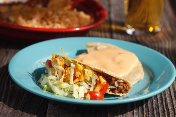 Part of El Original Combo #1: A picadillo beef crispy taco, one cheese enchilada with chili gravy, one beef tamale, a chile con queso tostada, guacamole, rice and beans.