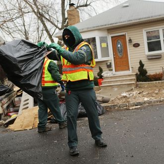 NEW YORK, NY - FEBRUARY 05: Sanitation workers thrrow out debris from a flood damaged home in Oakwood Beach in Staten Island on February 5, 2013 in New York City. In a program proposed by New York Governor Andrew Cuomo, New York state could spend up to $400 million to buy out home owners whose properties were destroyed by Superstorm Sandy. The $50.5 billion disaster relief package, which was passed by Congress last month, would be used to fund the program. If the program is adopted, homeowners would be relocated and their land would be left as a natural barrier to help absorb future floods waters. (Photo by Spencer Platt/Getty Images)