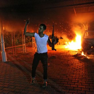An armed man waves his rifle as buildings and cars are engulfed in flames after being set on fire inside the US consulate compound in Benghazi late on September 11, 2012. An armed mob protesting over a film they said offended Islam, attacked the US consulate in Benghazi and set fire to the building, killing one American, witnesses and officials said. 