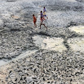 Children walk on the dry bed of parched mud that is the