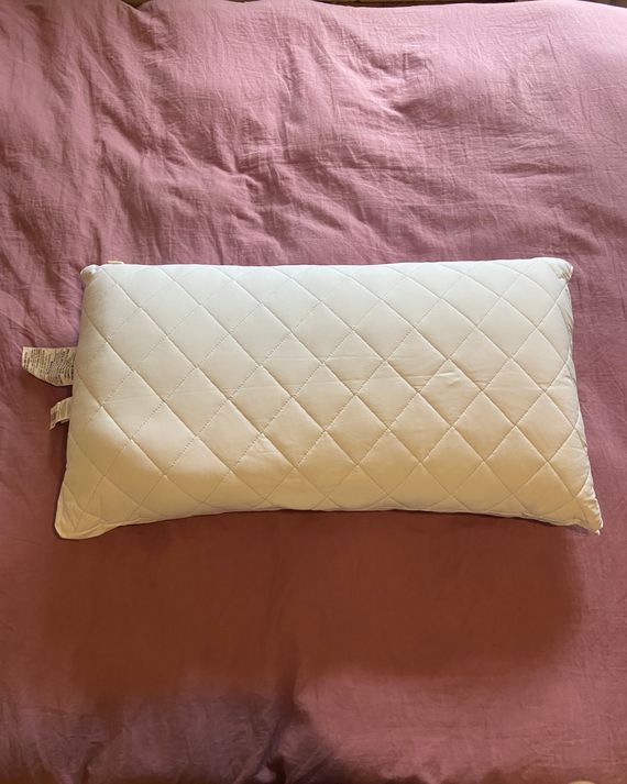 A white king size pillow on a pink duvet.