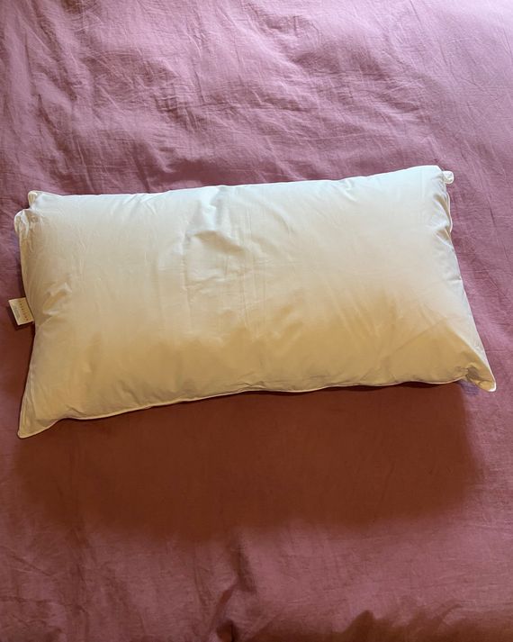 A white king size pillow on a pink duvet.