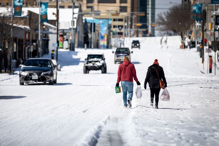 People carrying groceries up a snowy hill in Austin.