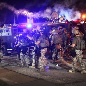 FERGUSON, MO - AUGUST 17: Police advance while sending a volley of tear gas toward demonstrators protesting the killing of teenager Michael Brown on August 17, 2014 in Ferguson, Missouri. Police shot smoke and tear gas into the crowd of several hundred as they advanced near the police command center which has been set up in a shopping mall parking lot. Brown was shot and killed by a Ferguson police officer on August 9. Despite the Brown family's continued call for peaceful demonstrations, violent protests have erupted nearly every night in Ferguson since his death. (Photo by Scott Olson/Getty Images)