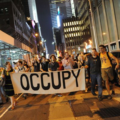 New york, United States. 30th May 2012 -- Protesters carry a large 'Occupy' banner as they march in the streets. -- Occupy Wall Street has a march in New York in solidarity with the Quebec students striking over student fees and Bill 78, which effectively outlaws most protests, who use kitchen pots and pans as their symbol.