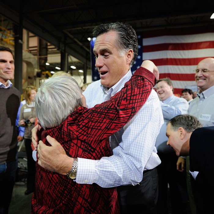 CEDAR RAPIDS, IA - DECEMBER 09: Republican presidential hopeful and former Massachusetts Gov. Mitt Romney (R) hugs supporter Joni Scotter, from Marion, Iowa, as his son Josh Romney (L) looks on at a town hall meeting at Diamond V South Plant on December 9, 2011 in Cedar Rapids, Iowa. Romney is campaigning in the state one month before the Iowa caucuses and one day before the GOP presidential debate. (Photo by Kevork Djansezian/Getty Images)