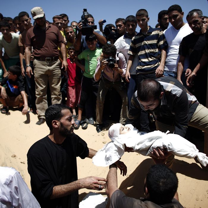 Relatives of seven-month-old Ali Deif, the son of Hamas's military commander Mohammed Deif, place his body into a grave during his funeral at the Beit Lahia cemetery in the northern Gaza Strip on August 20, 2014. Several thousand mourners joined the funeral procession for the wife and baby son of Hamas's military commander, angrily demanding revenge against Israel. 