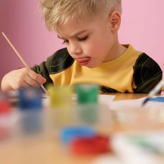 Little boy painting, sticking his tongue out