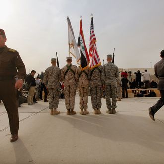 BAGHDAD, IRAQ - DECEMBER 15: U.S. Military personnel holding the US flag, Iraq flag, and the US Forces Iraq colors stand as an Iraqi Army officer (L) walks past before the start of a casing ceremony where the United States Forces- Iraq flag was retired, signifying the departure of United States troops from Iraq, at the former Sather Air Base on December 15, 2011 in Baghdad, Iraq. United States forces are scheduled to entirely depart Iraq by December 31, there are currently around 4,000 troops remaining in Iraq.(Photo by Mario Tama/Getty Images)