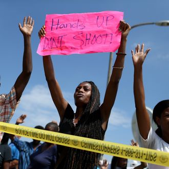 ST. LOUIS, MO - AUGUST 19: People raise their arms while chanting, 