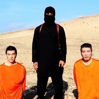 A video released by ISIS on social media Tuesday, Jan. 20, 2015, purportedly shows a masked man standing over two kneeling men in orange jumpsuits. The terror groups threatened to kill the two Japanese hostages unless Tokyo pays $200 million.