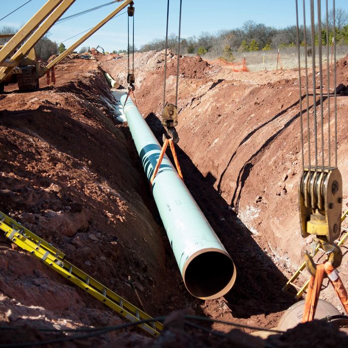 A sixty-foot section of pipe is lowered into a trench during construction of the Gulf Coast Project pipeline in Prague, Oklahoma, U.S., on Monday, March 11, 2013. The Gulf Coast Project, a 485-mile crude oil pipeline being constructed by TransCanada Corp., is part of the Keystone XL Pipeline Project and will run from Cushing, Oklahoma to Nederland, Texas. 