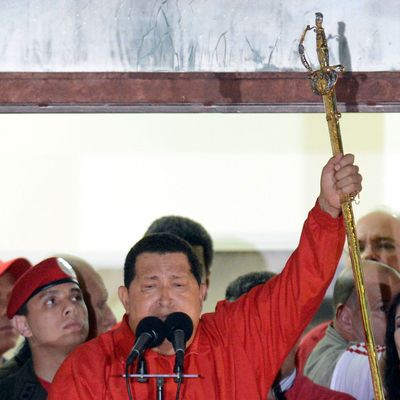 Venezuelan President Hugo Chavez (C) holds the sword of South American liberator Simon Bolivar while speaking to supporters after receiving news of his reelection in Caracas on October 7, 2012. According to the National Electoral Council, Chavez was reelected with 54.42% of the votes, beating opposition candidate Henrique Capriles, who obtained 44.47%. AFP PHOTO/JUAN BARRETO