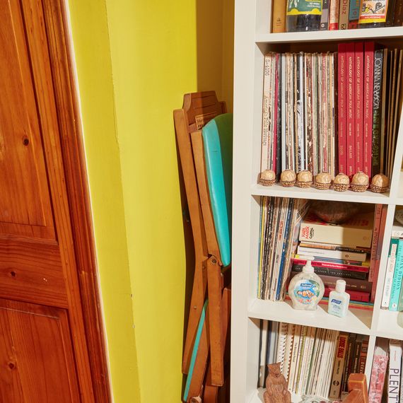 Folding chairs tucked between a wall and a bookshelf