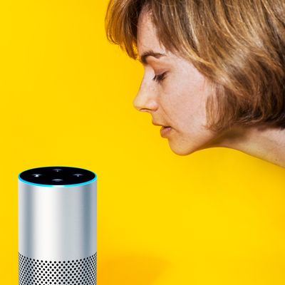 A woman leans toward an Amazon Echo device.