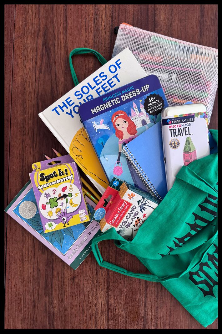 A tote bag lying on a table with the Spot It card game, a box of Eeboo Story Cards, and some books splaying out of it.