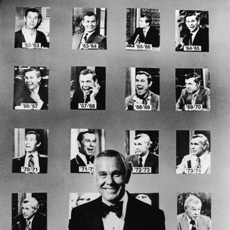 American talk show host and comedian Johnny Carson (1925 - 2005) wears a tuxedo and poses in front of portraits of him from his first twenty years as host of the NBC late night talk show 'The Tonight Show,' early 1980s. (Photo by NBC Television/Getty Images)