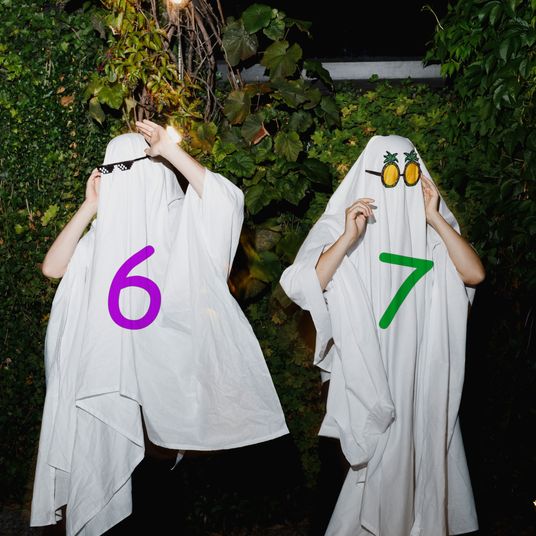 Happy couple wearing eyeglasses and ghost costumes at Halloween party
