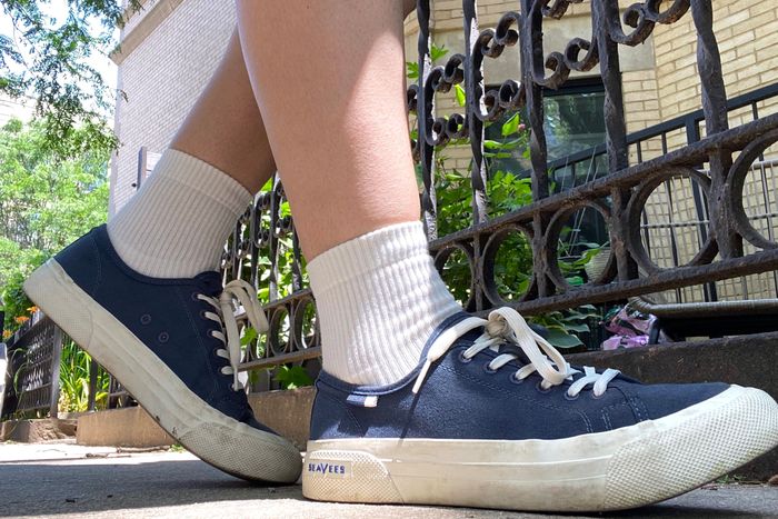View from ground level of feet in a pair of Seavees sneakers with white ribbed Bombas quarter socks.