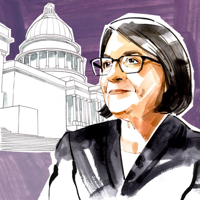 An illustration of a woman with cropped black hair and wearing square black glasses, with the U.S. Capitol looming in the background.