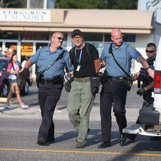 FERGUSON, MO - AUGUST 18: Getty Images staff photographer Scott Olson is placed into a paddy wagon after being arrested by police as he covers the demonstration following the shooting death of Michael Brown on August 18, 2014 in Ferguson, Missouri. Protesters have been vocal asking for justice in the shooting death of Michael Brown by a Ferguson police officer on August 9th. (Photo by Joe Raedle/Getty Images)