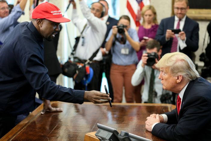 Rapper Kanye West shows President Donald Trump a photo of a plane on his iPhone during an Oval Office meeting on October 11, 2018.