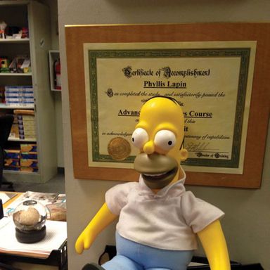 “Here is the Homer Simpson doll on Phyllis's desk. They used this doll as set dressing in the pilot, and our showrunner Greg Daniels asked Matt Groening if he minded if they continued to use it. Well, he didn't mind! And so Homer stayed there for nine years.”