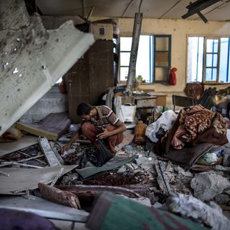 A Palestinian scout collects human remains from a classroom inside a UN school in the Jabalia refugee camp after the area was hit by shelling on July 30, 2014. Israeli bombardments early on July 30 killed 