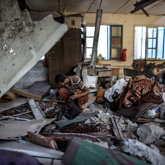 A Palestinian scout collects human remains from a classroom inside a UN school in the Jabalia refugee camp after the area was hit by shelling on July 30, 2014. Israeli bombardments early on July 30 killed 