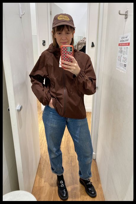 Mirror selfie showing Strategist senior writer Liza Corsillo trying on a brown check Uniqlo windbreaker.