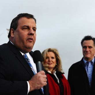 Republican presidential hopeful Mitt Romney (R) and his wife Ann Romney look on as New Jersey Governor Chris Christie speaks during a campaign rally outside a grocery store in Des Moines, Iowa, on December 30, 2011