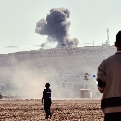 People watch smoke rising from the Syrian town of Ain al-Arab, known as Kobane by the Kurds, after an air strike, on October 8, 2014 in the Turkish-Syrian border, in the southeastern village of Mursitpinar, Sanliurfa province. AFP PHOTO / ARIS MESSINIS (Photo credit should read ARIS MESSINIS/AFP/Getty Images)