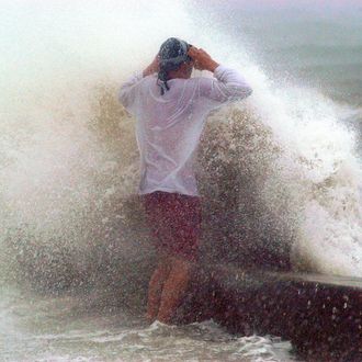 A wave cause by the storm surge of Hurricane Jeanne breaks over a seawall as a man stands on it September 26, 2004 in St. Petersburg, Florida. 