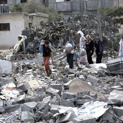 Palestinians carry their possessions as they walk on the rubble of buildings destroyed during the Israeli military offensive, close to the Rafah refugee camp, in southern Gaza Strip, on August 4, 2014. Civil defence workers and medics are searching the neighborhood looking for victims of the ongoing Israeli military operation which has killed some 1,829 Palestinians, mainly civilians. AFP PHOTO / MAHMUD HAMS (Photo credit should read MAHMUD HAMS/AFP/Getty Images)