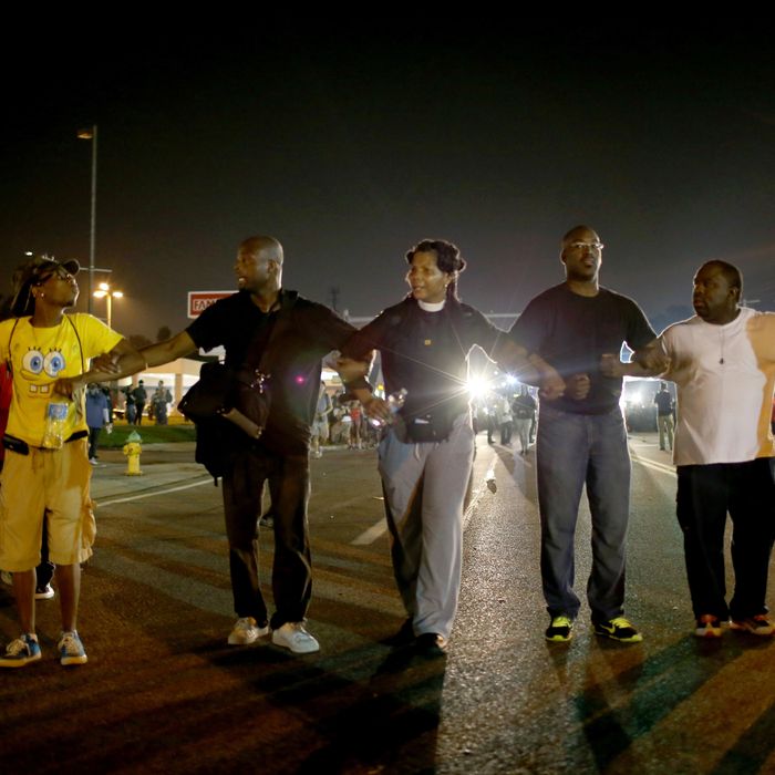 FERGUSON, MO - AUGUST 18: Demonstrators protesting the shooting death of Michael Brown walk down the street on August 18, 2014 in Ferguson, Missouri. Protesters have been vocal asking for justice in the shooting death of Michael Brown by a Ferguson police officer on August 9th. (Photo by Joe Raedle/Getty Images)