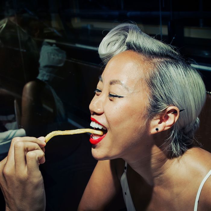 A woman sensually eating a single French fry at the restaurant Pastis