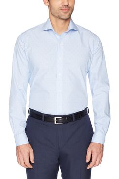 A male model wearing a Supima cotton non-iron slim fit dress shirt button-down with subtle blue and white stripes with navy trousers and a black belt that has a square silver buckle. The Strategist - A Bunch of Men’s Button Downs (From $16) Are on Sale at Amazon