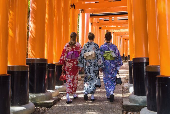 Kyoto, Japan - April 17, 2023: three European women in Kimono walking through Torii path at Fushimi Inari-Taisha Shrine, that is the head shrine of th