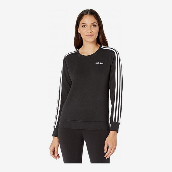 A classic adidas Essential black fleece crew sweatshirt with the Adidas logo and 3 Stripes down the arms and black leggings on a model. 